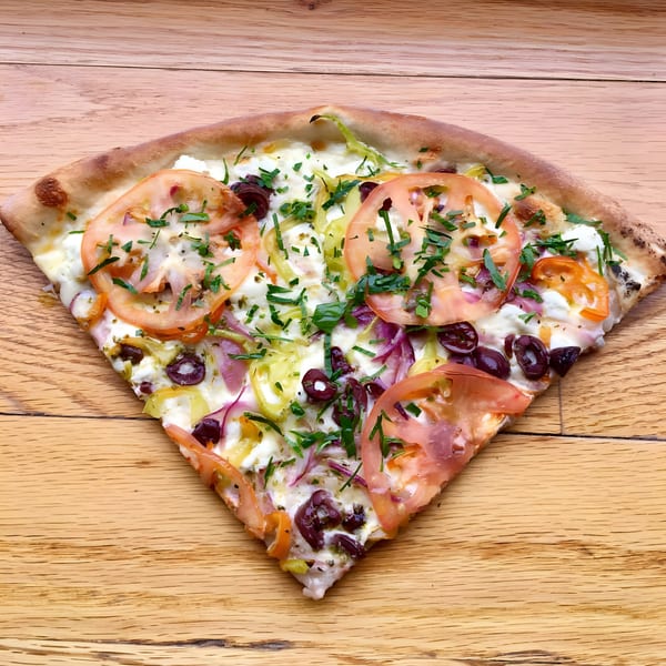 A single slice of All Star Pizza Bar's white pizza with tomatoes, olives, peppers, and herbs.